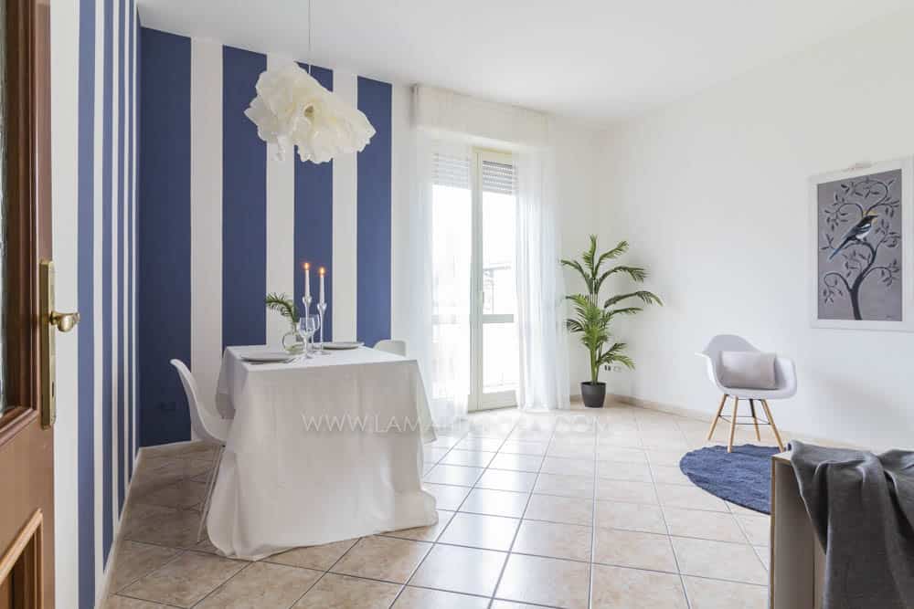 soggiorno con parete a righe verticali blu e bianche, tavola imbandita con candelabri e lampadario